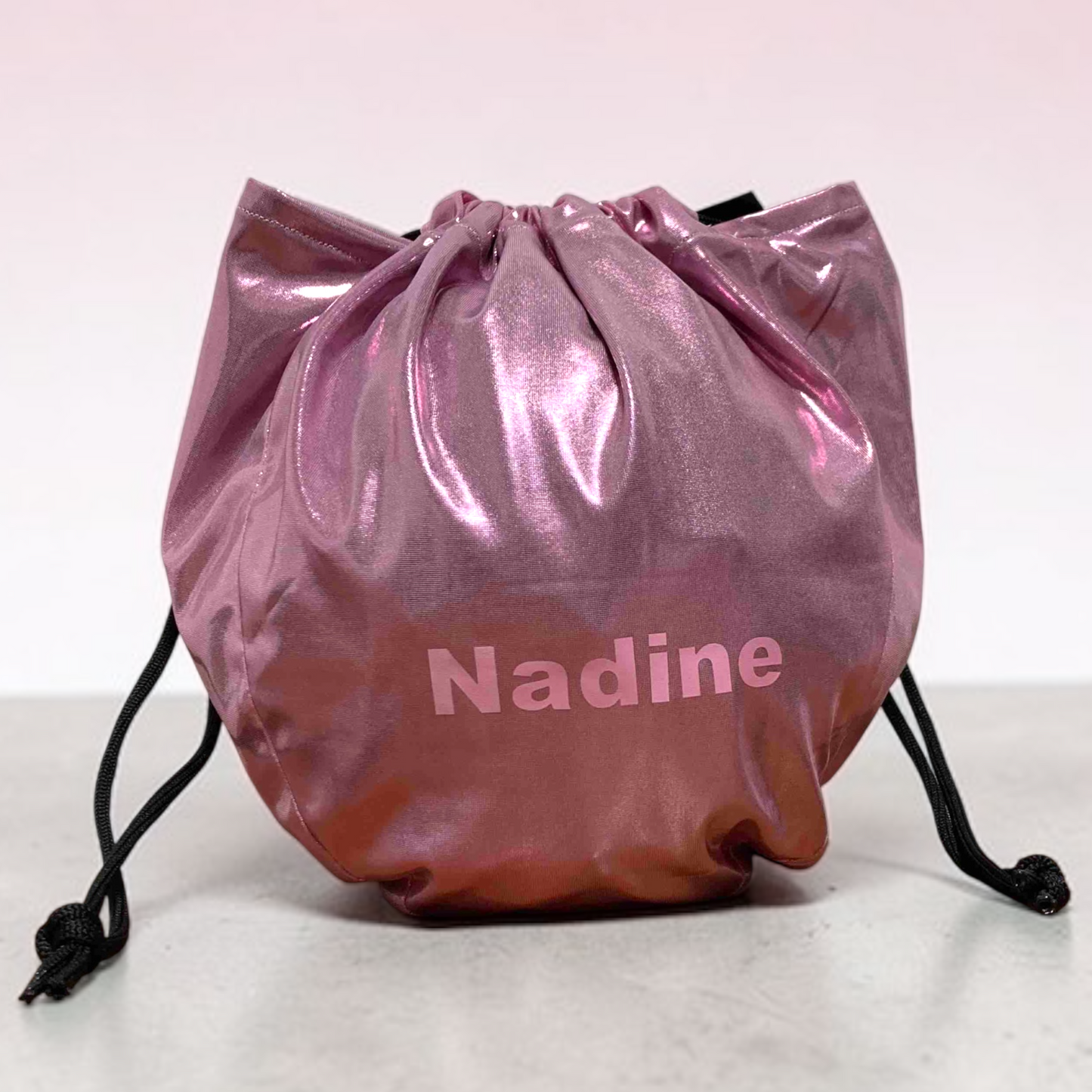 Pink drawstring bag with 'Nadine' printed on it against a white background