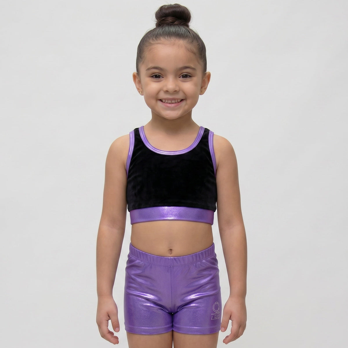 Young girl wearing a black and purple athletic outfit on a white background