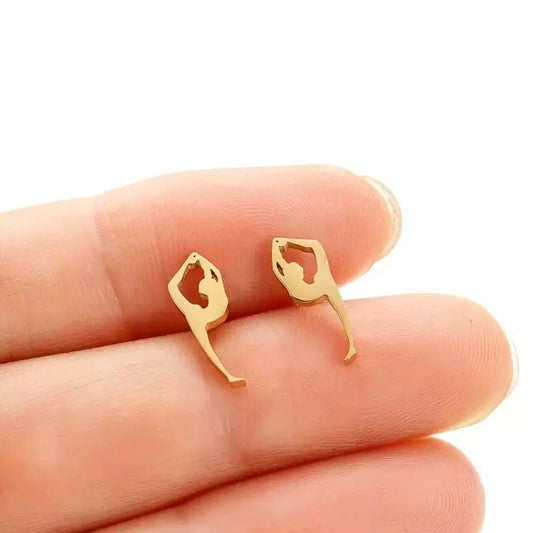 A pair of gold-tone gymnast silhouette earrings displayed on a hand.