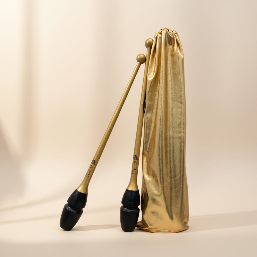 Pair of brass clubs with black ends in a gold carrying case on a beige background