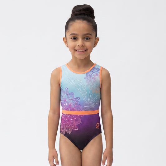 A young girl with her hair in a high bun stands against a light gray studio background wearing a sleeveless leotard with a purple, pink, and blue gradient floral design.