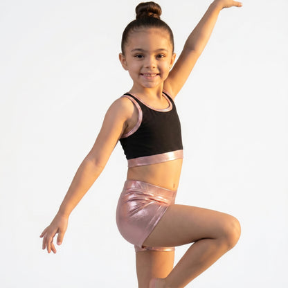 Young girl in a black and pink dance outfit posing against a white background