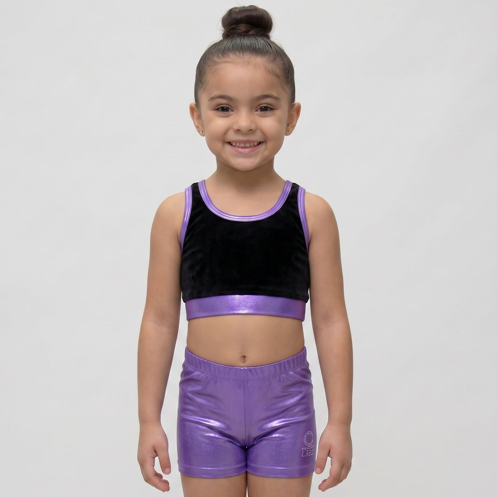 Young girl wearing a black and purple athletic outfit on a white background