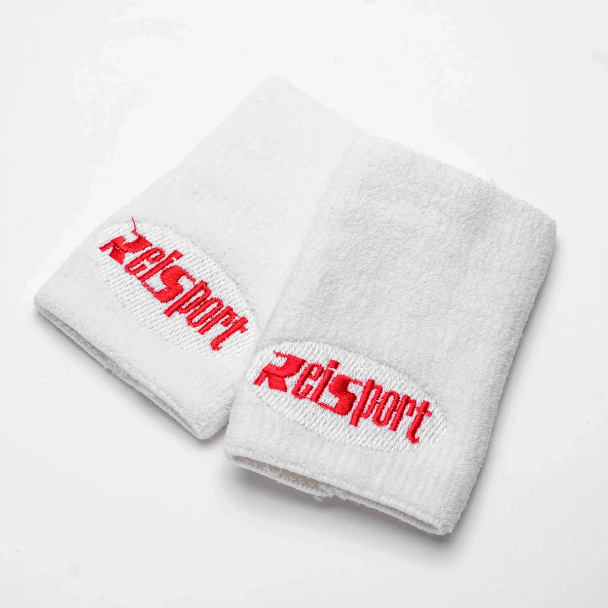 Two white cotton wristbands with red embroidered 'Reisport' logos, displayed on a clean white background.