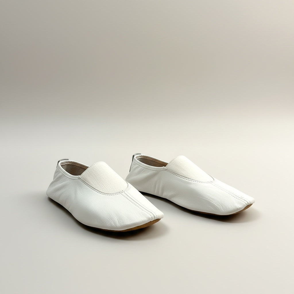Pair of white loafers on a light gray background